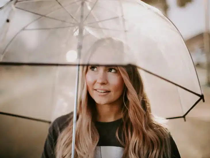 woman smiling and using clear umbrella during day