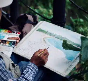 man holding brown and black pen painting seashore