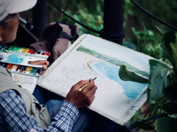 man holding brown and black pen painting seashore